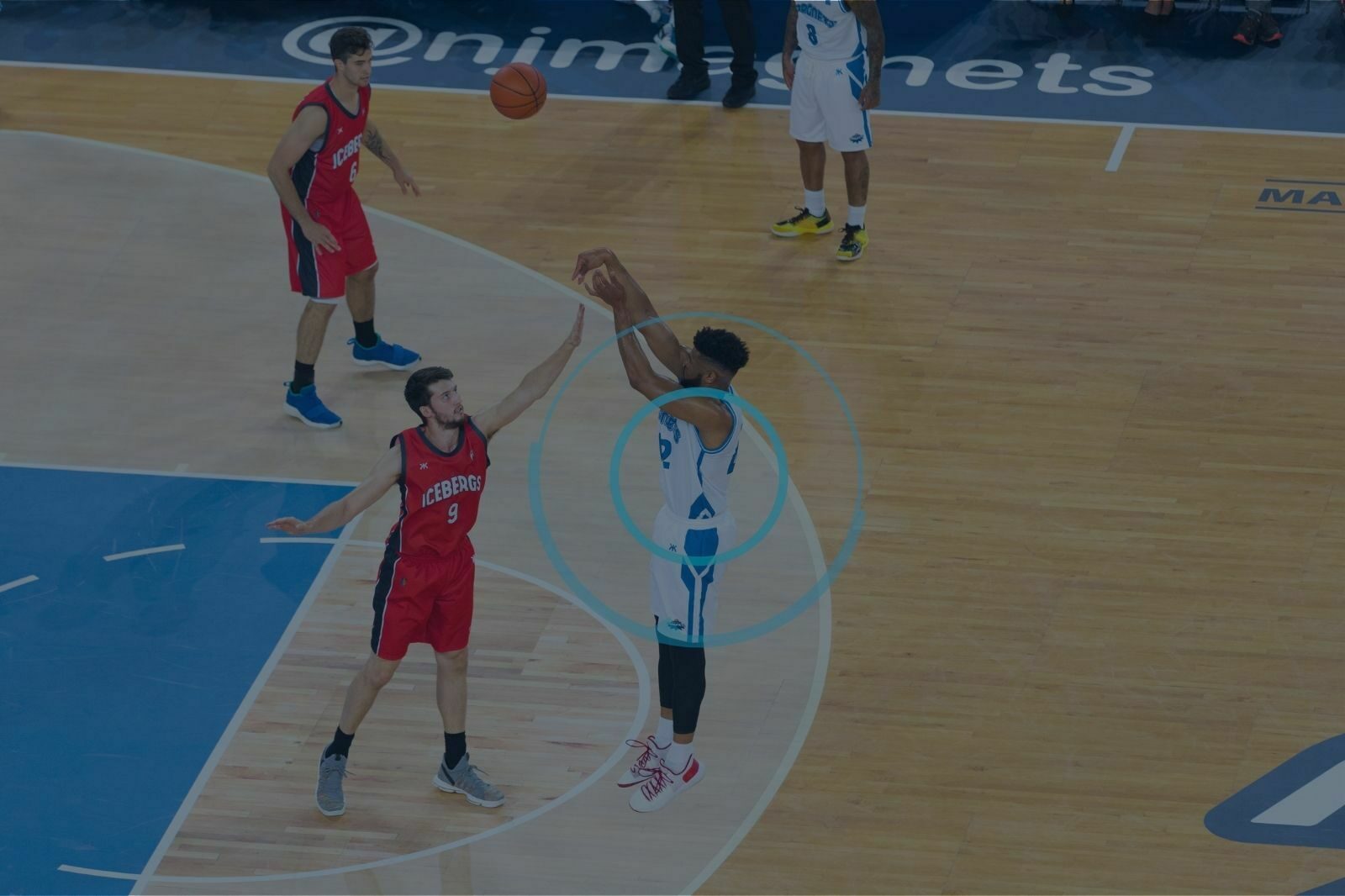 Basketball player taking a jump shot in a game as his mechanical loading is being monitored by a player tracking system.