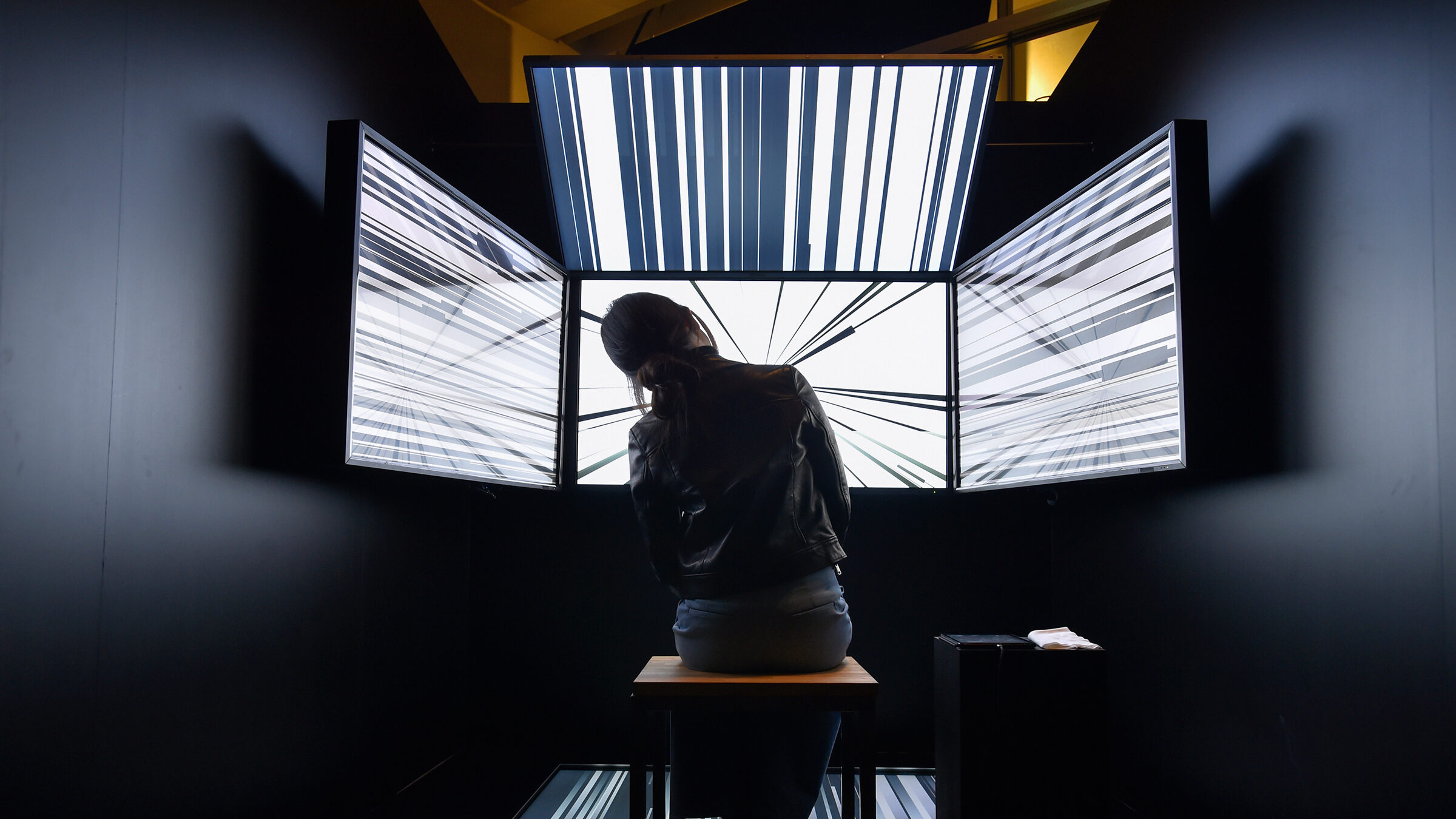 Person sits in front of three screens