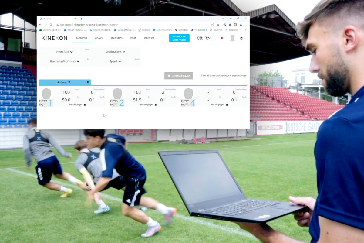 A coach uses football trackers to monitor players during a training session and checks the data on his laptop in real-time.