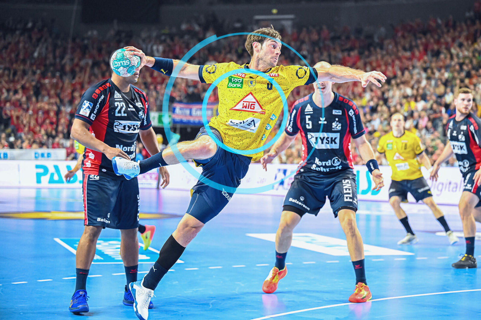 A team handball player leaps into the air to take a shot while wearing a player tracker that his coach is using to monitor his load management.
