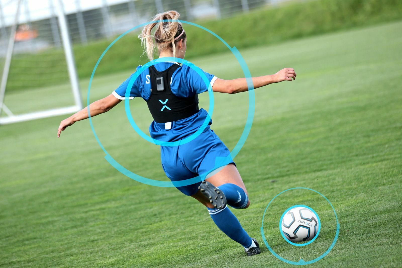 A female soccer player kicking the ball towards the goal.