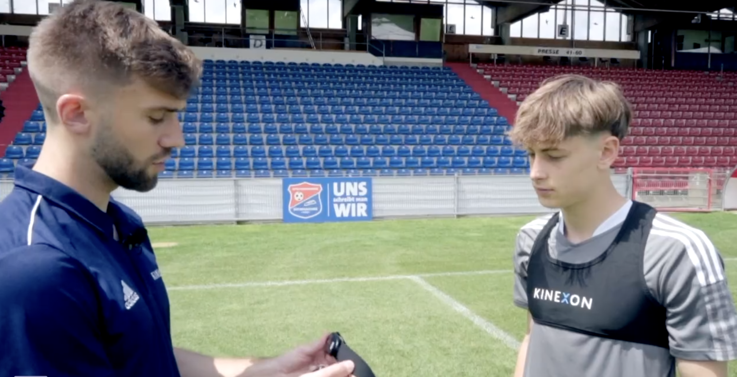 A coach explains to a player how a sports heart rate monitor is to be worn.