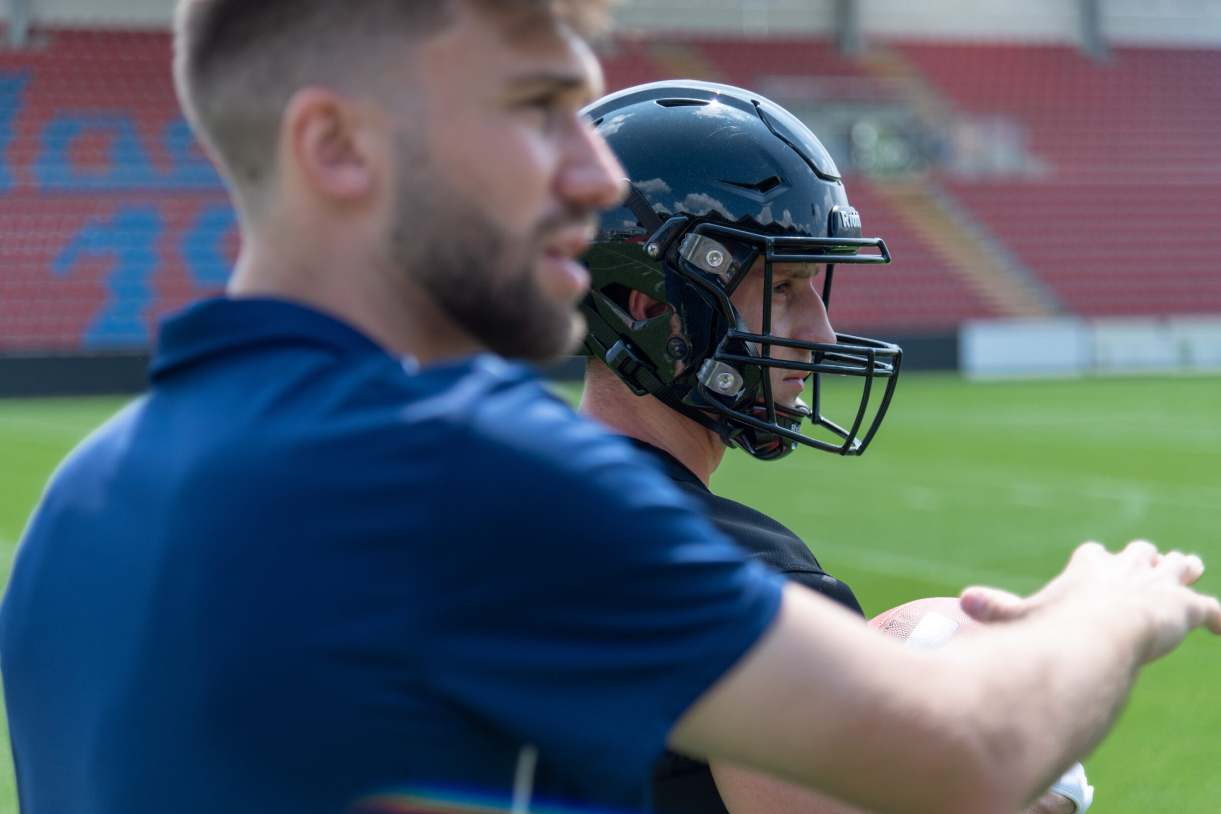 A tackle football coach talks over strategy with a wide receiver during a timeout. Football coaches now use sports data analytics to help make decisions.