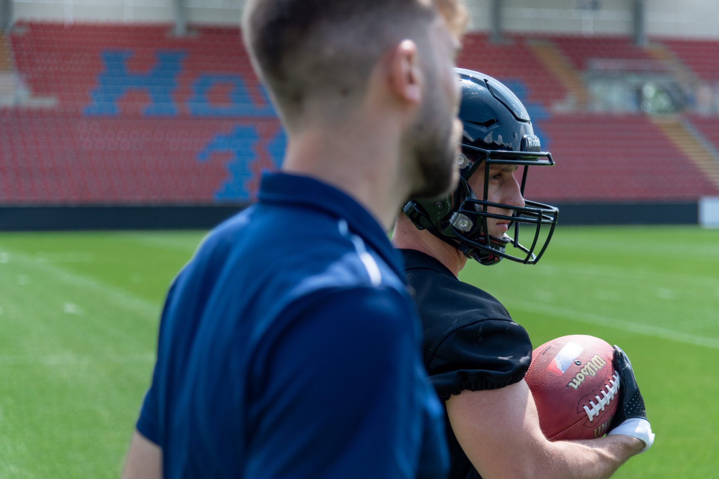 A sports scientist talks to a football player about his mechanical loading during a practice.