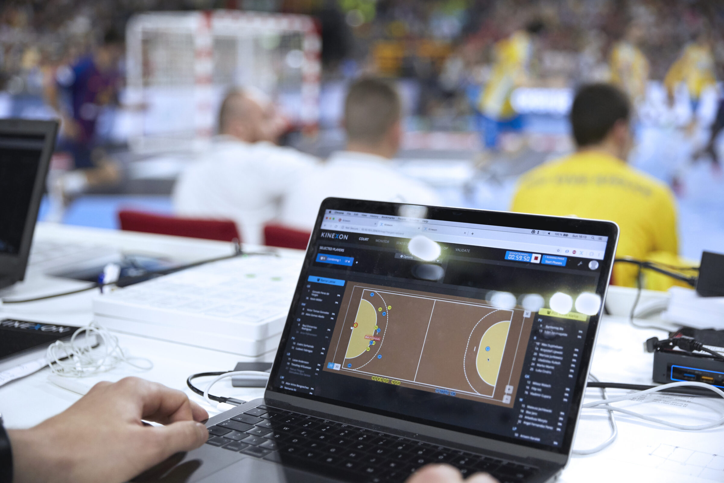 A trainer uses a laptop to monitor a player's load management during a game.