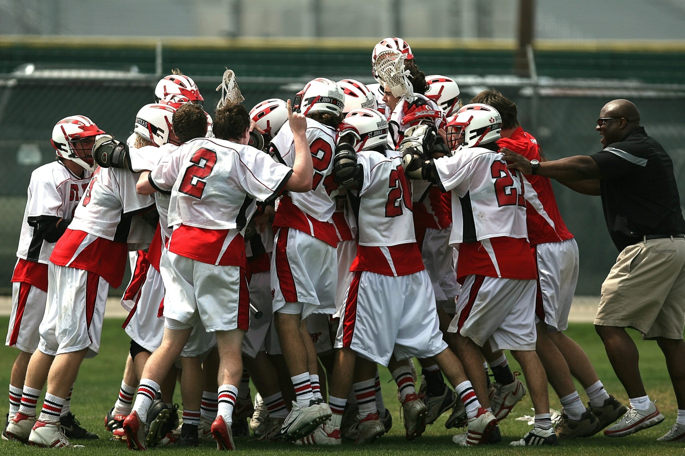 A lacrosse team celebrates a win after a big game and then will review the sports data analytics their player tracking devices collected..