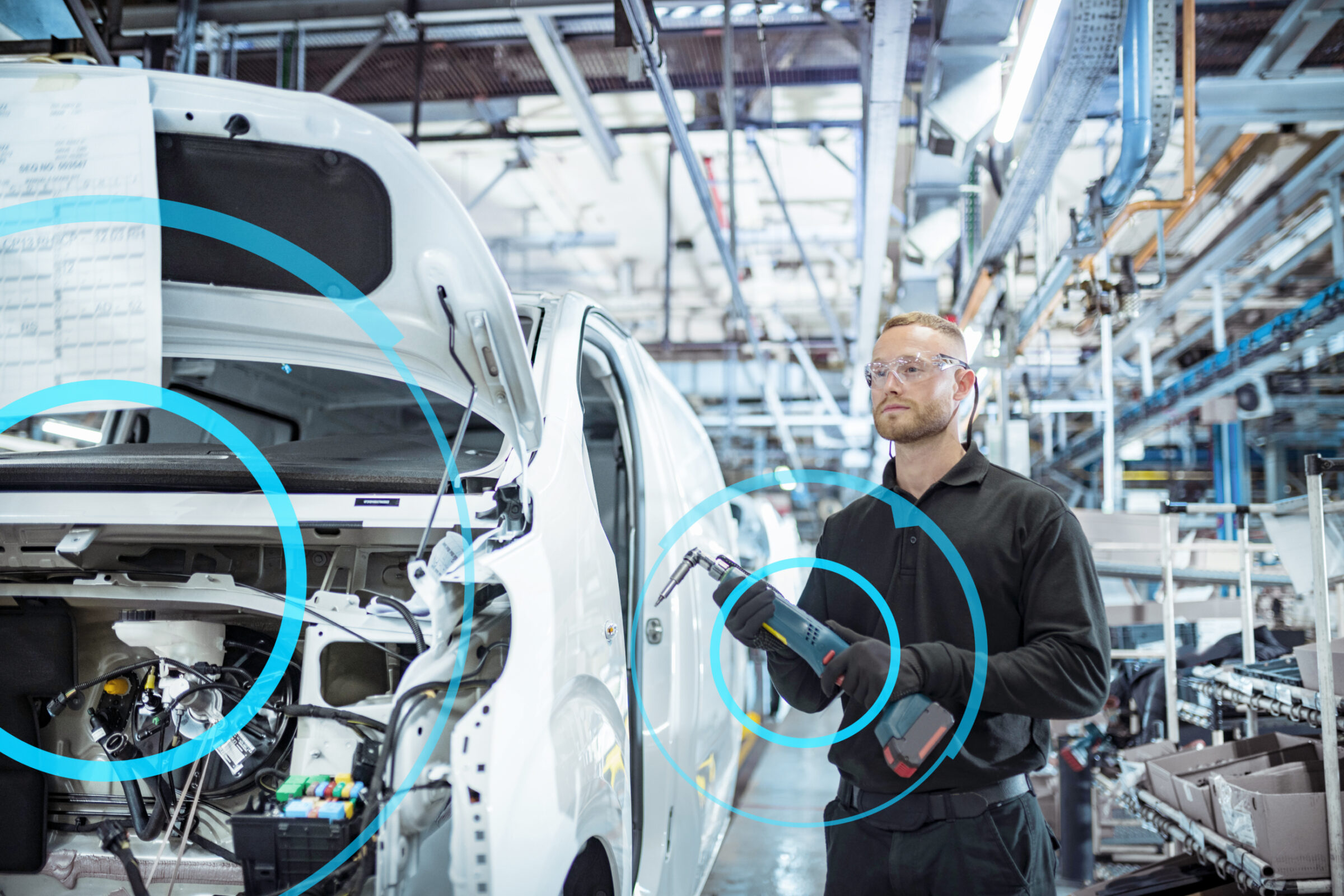 Worker with tool on car in automotive factory with blue designed circles