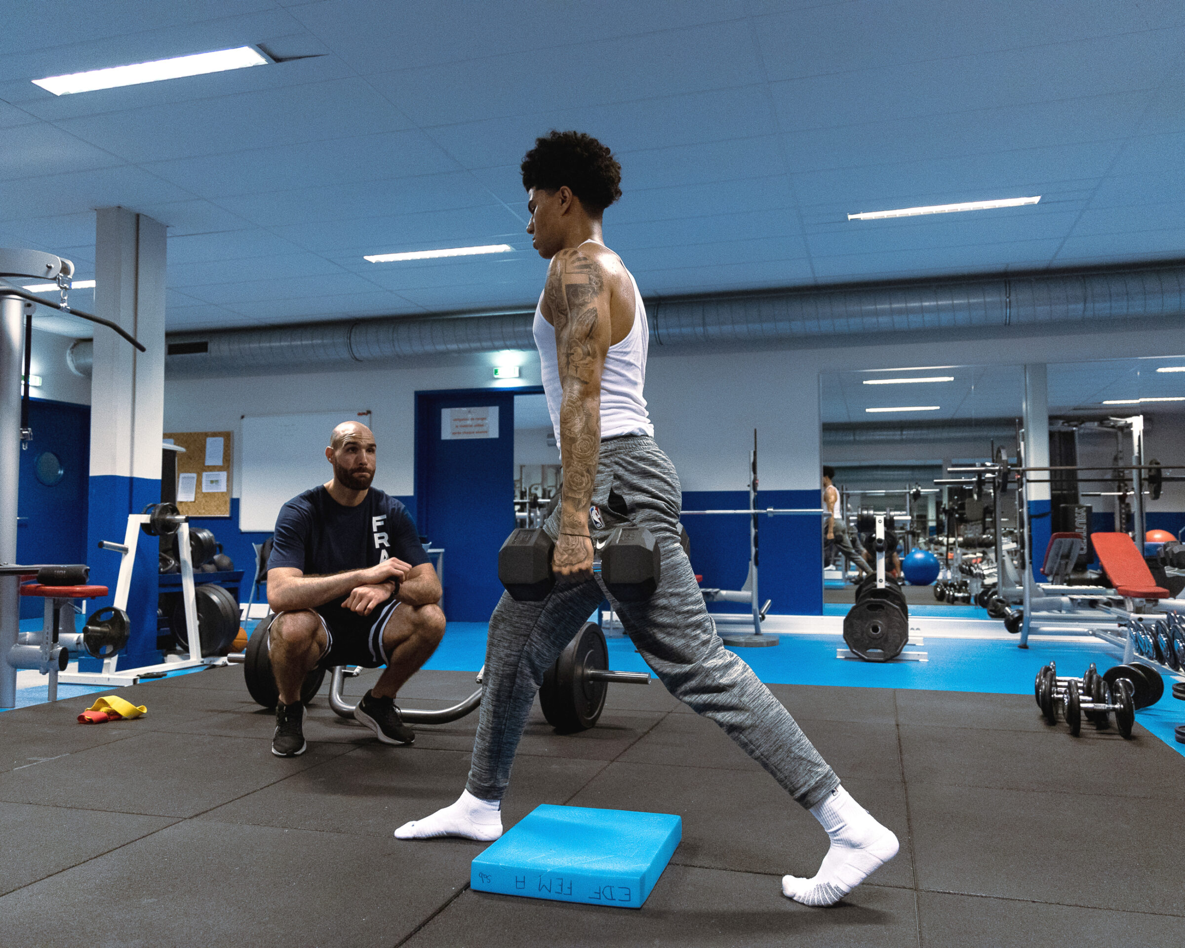 An American football player works out under the watchful eye of a sports performance trainer.