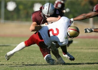 A player makes a tackle during an American football game, where many coaches are now using player tracking devices to help prevent the most common football injuries.