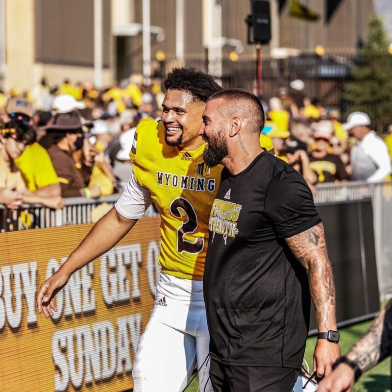 A player on the University of Wyoming Football team talks to a coach about his performance and the sports analytics they use during a game..