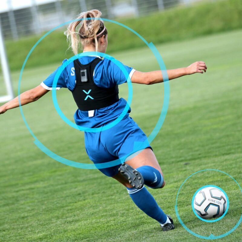 A female soccer player kicking the ball towards the goal.